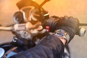 Hand in leather glove and with watch on the helm of a motorcycle